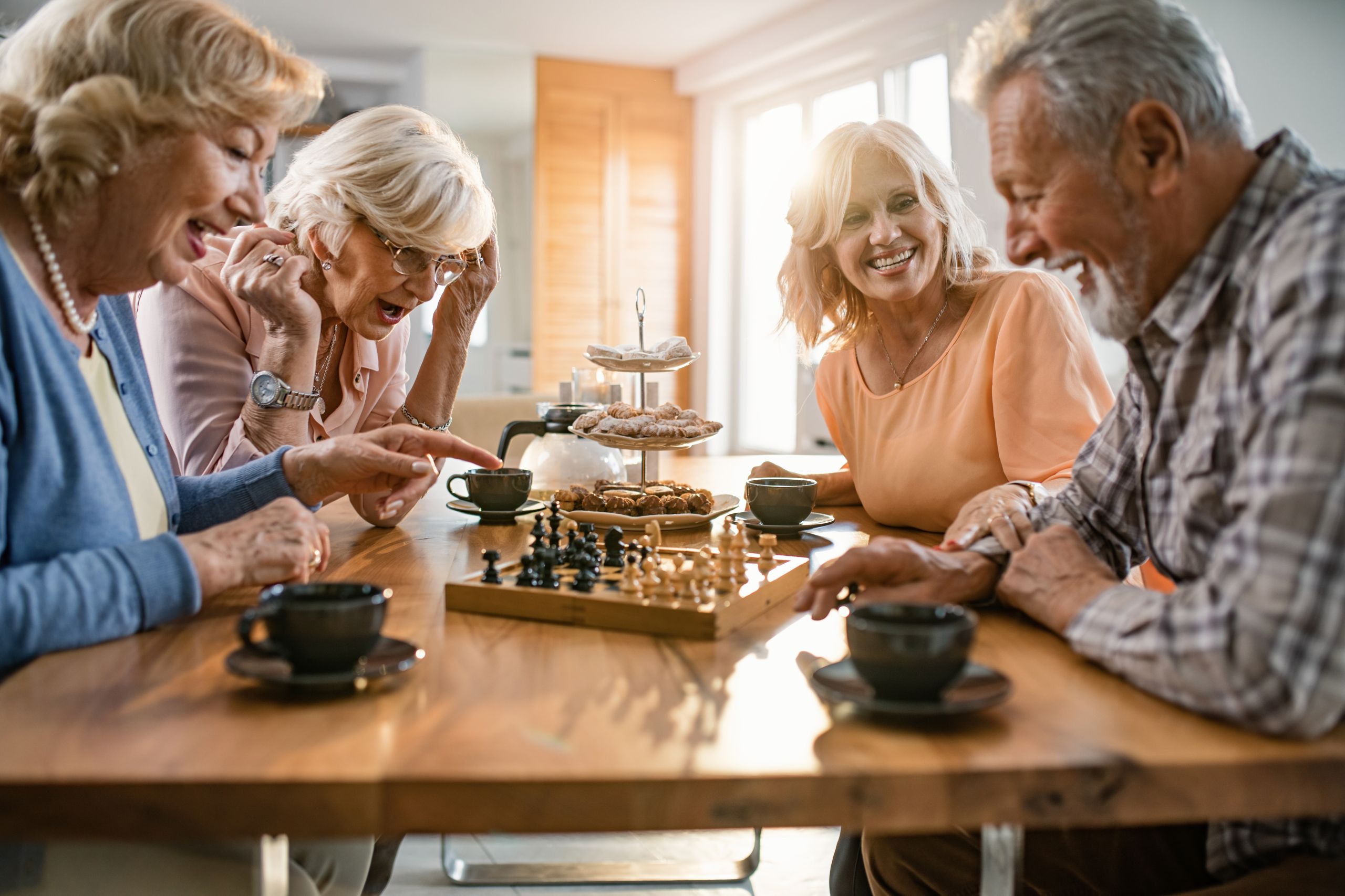 Cheerful seniors having fun while playing chess at home.